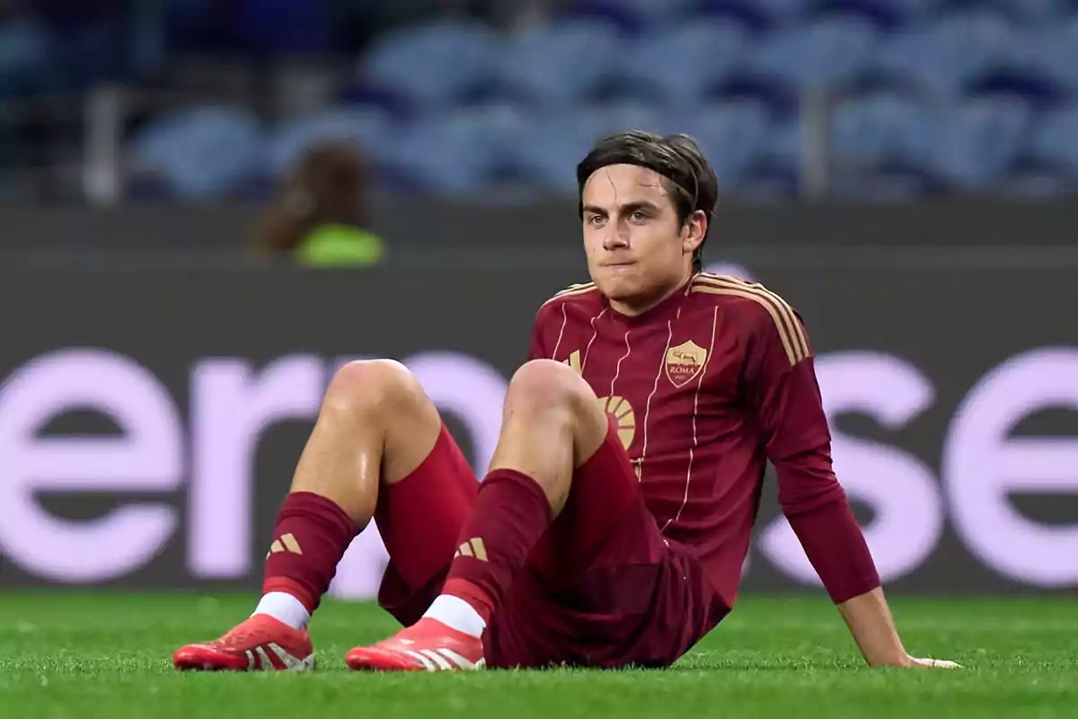 A player in a red uniform is sitting on the field during a match. A player in a red uniform is sitting on the field during a match.