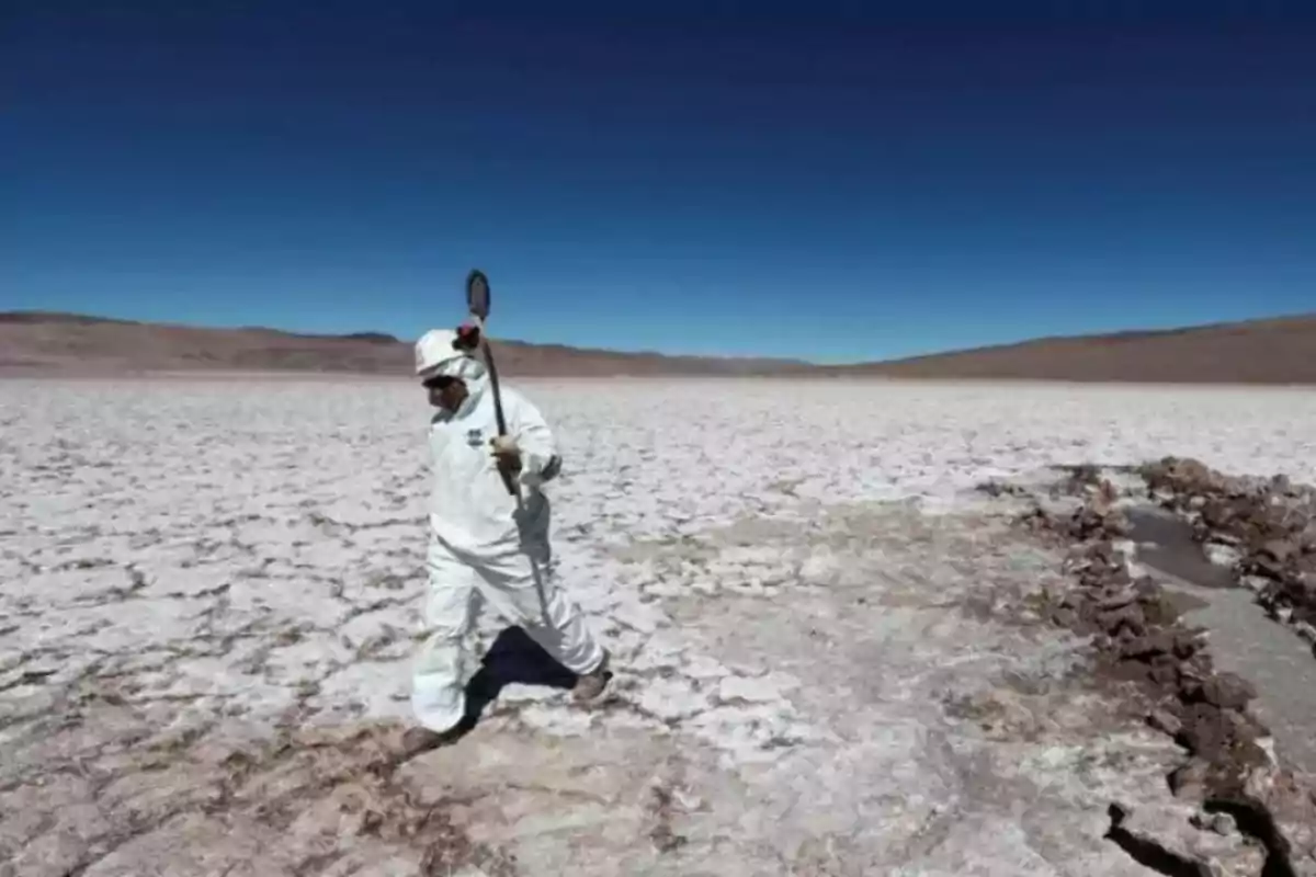 Persona con traje protector caminando por un salar bajo un cielo despejado.