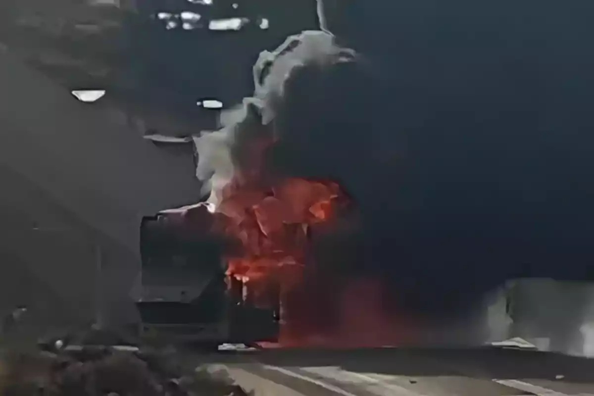 Bus engulfed in flames with a thick column of black smoke on a highway Bus engulfed in flames with a thick column of black smoke on a highway