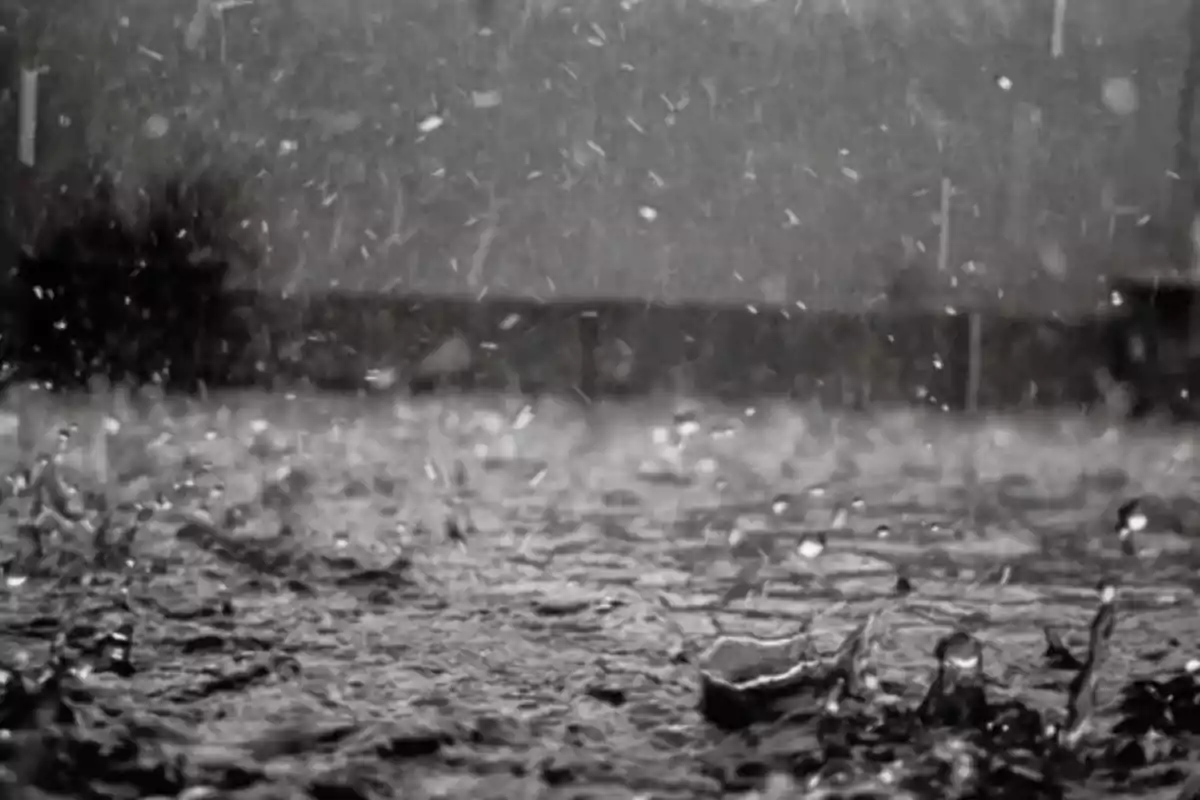 Lluvia intensa cayendo sobre una superficie mojada en un día oscuro.