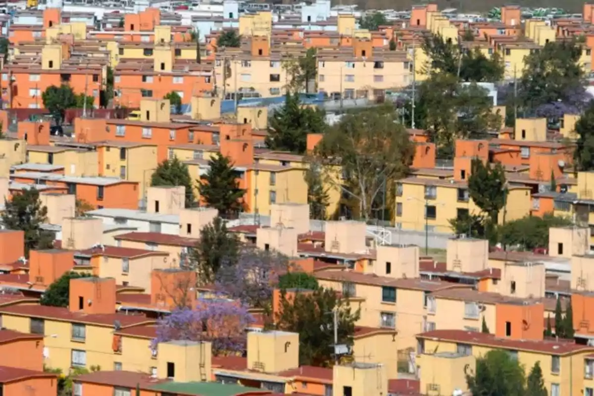 Conjunto de edificios residenciales de colores cálidos con árboles dispersos entre ellos.