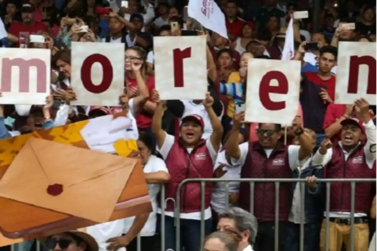 Un grupo de personas sostiene carteles con letras formando una palabra mientras están rodeados de una multitud; en primer plano hay un sobre sellado.