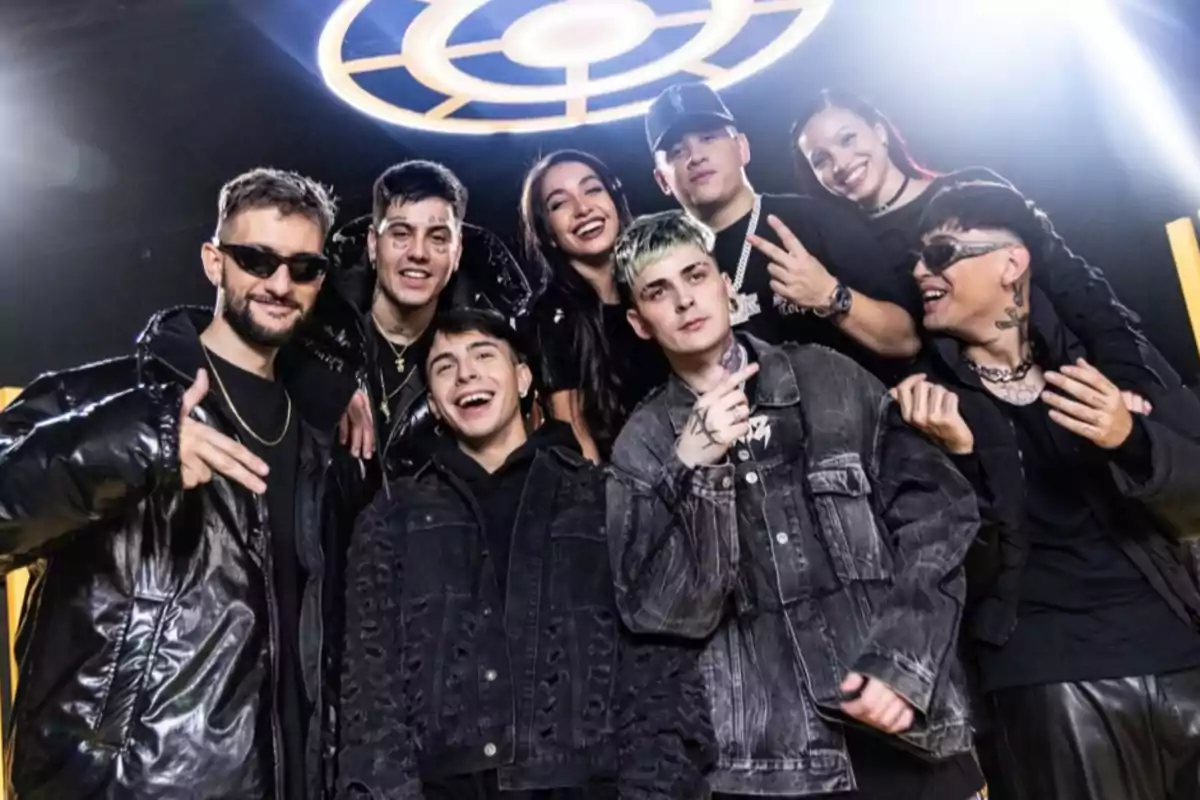 Un grupo de personas posando juntas con ropa oscura y sonriendo en un ambiente iluminado.