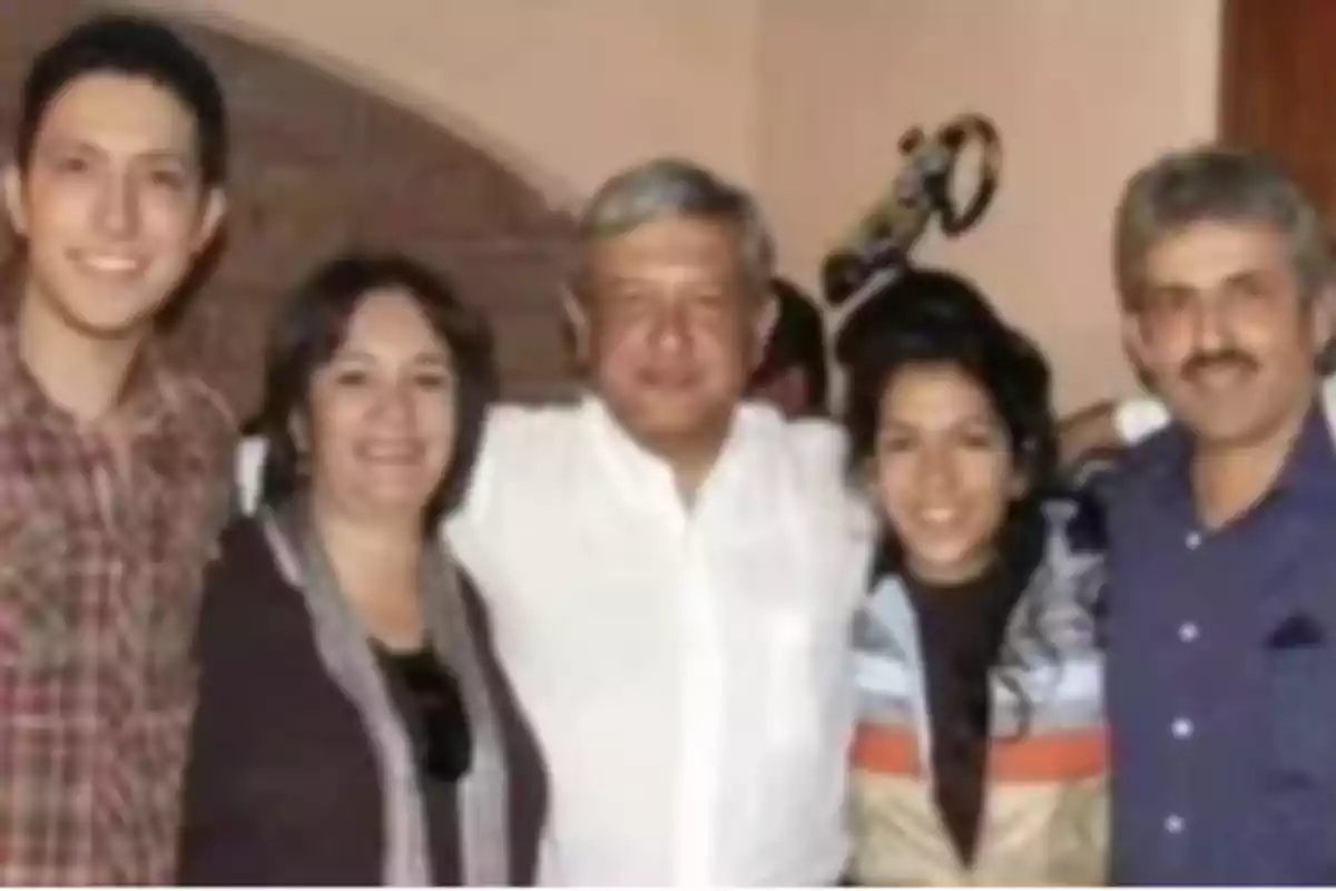 Un grupo de cinco personas posando juntas y sonriendo en un ambiente interior.