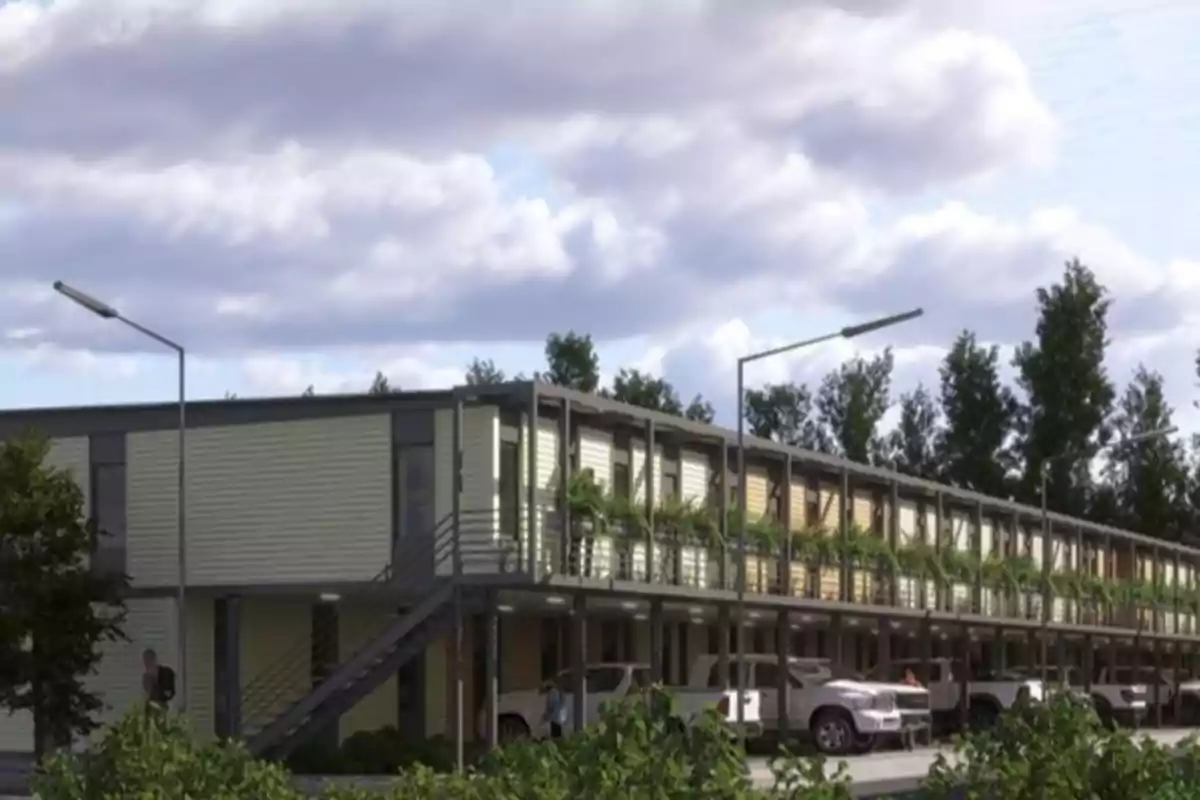 Edificio de dos pisos con balcones y estacionamiento en la planta baja rodeado de árboles y autos estacionados al frente Edificio de dos pisos con balcones y estacionamiento en la planta baja rodeado de árboles y autos estacionados al frente