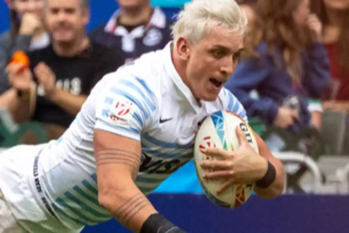 Rugby player in a white and light blue jersey running with the ball in his hands during a match Rugby player in a white and light blue jersey running with the ball in his hands during a match