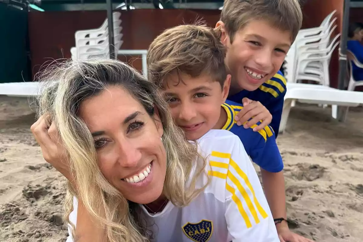 A smiling woman with two children on the beach, all wearing sports jerseys. A smiling woman with two children on the beach, all wearing sports jerseys.