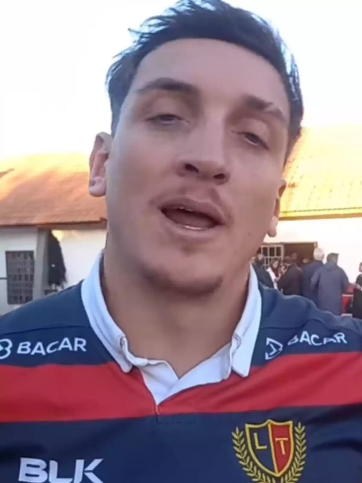 Man wearing a blue and red rugby jersey with an LT crest outdoors Man wearing a blue and red rugby jersey with an LT crest outdoors