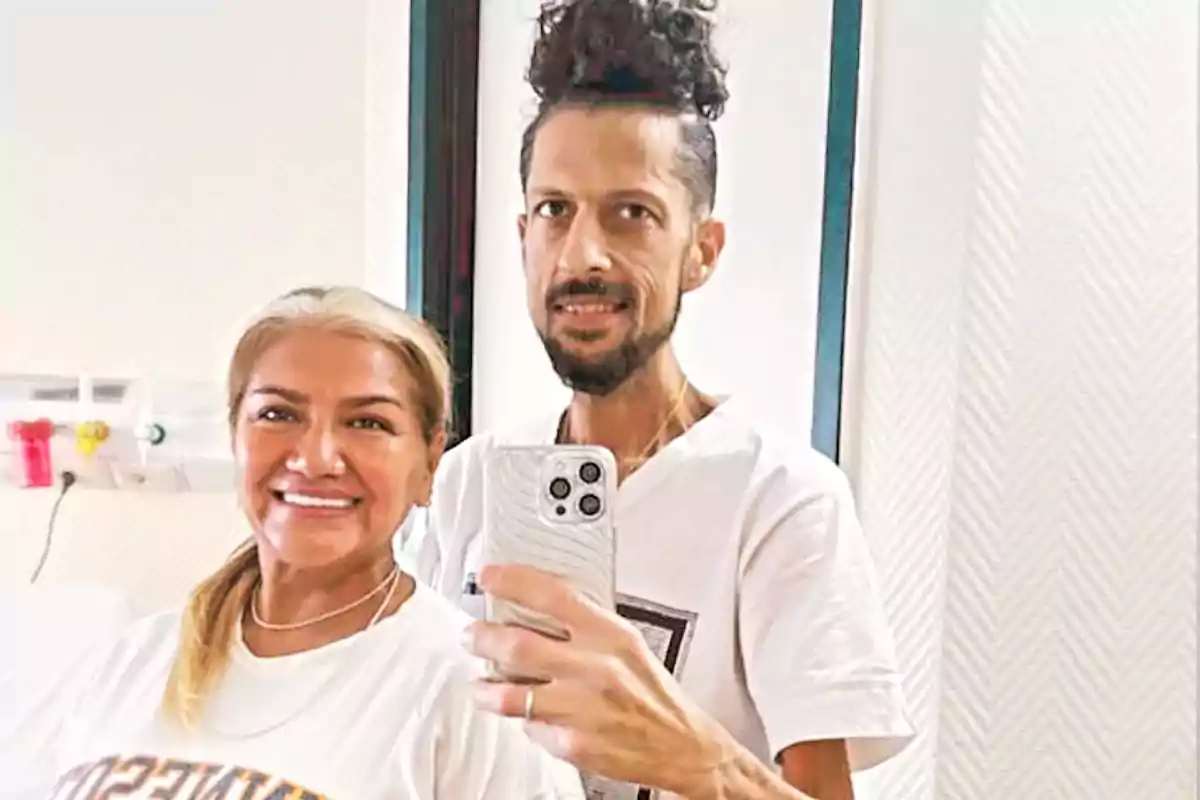 Dos personas sonríen mientras se toman una selfie frente a un espejo.