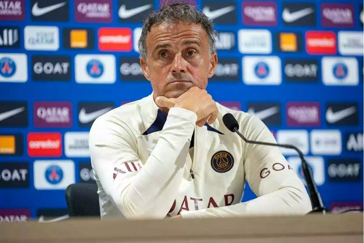 A man at a press conference with a background full of sports sponsor logos. A man at a press conference with a background full of sports sponsor logos.