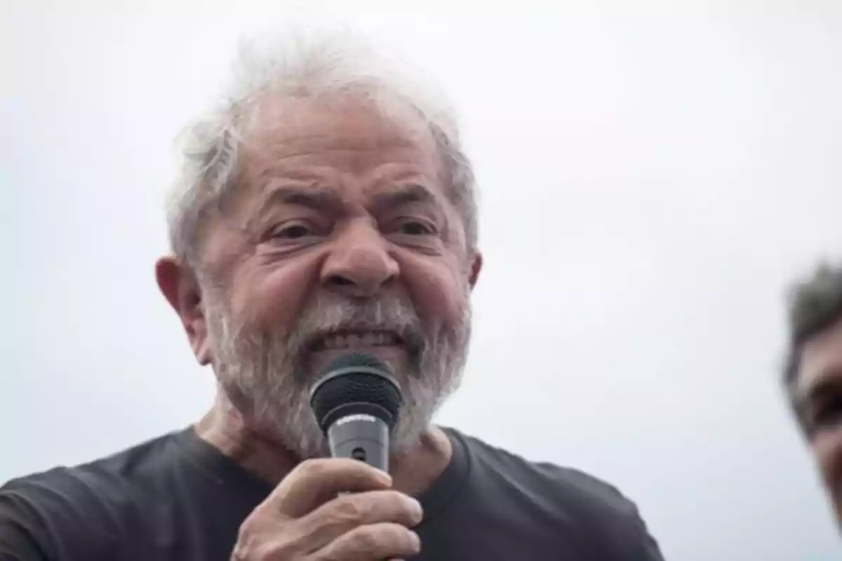 Hombre mayor con barba canosa hablando enérgicamente por un micrófono