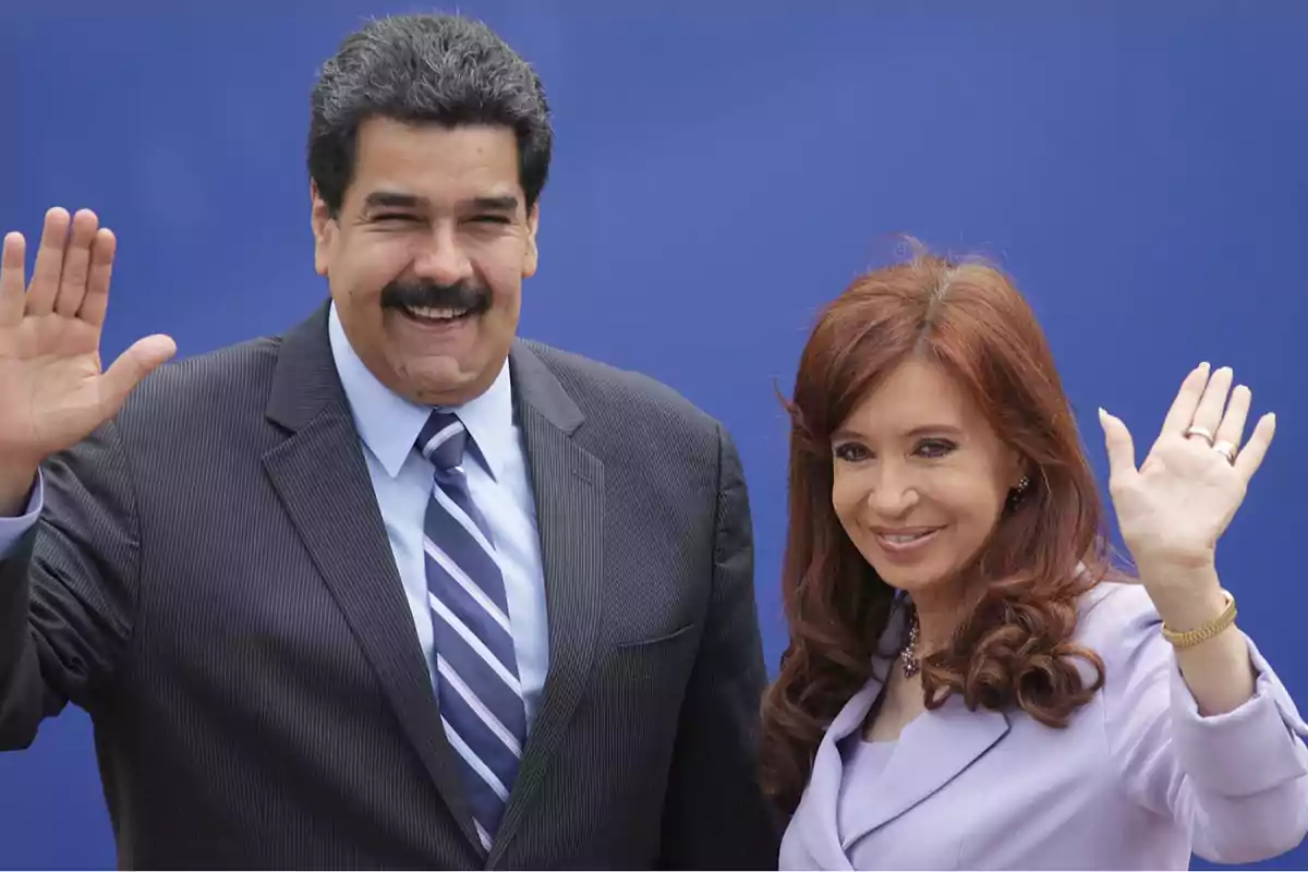 Dos personas sonriendo y saludando con la mano frente a un fondo azul.