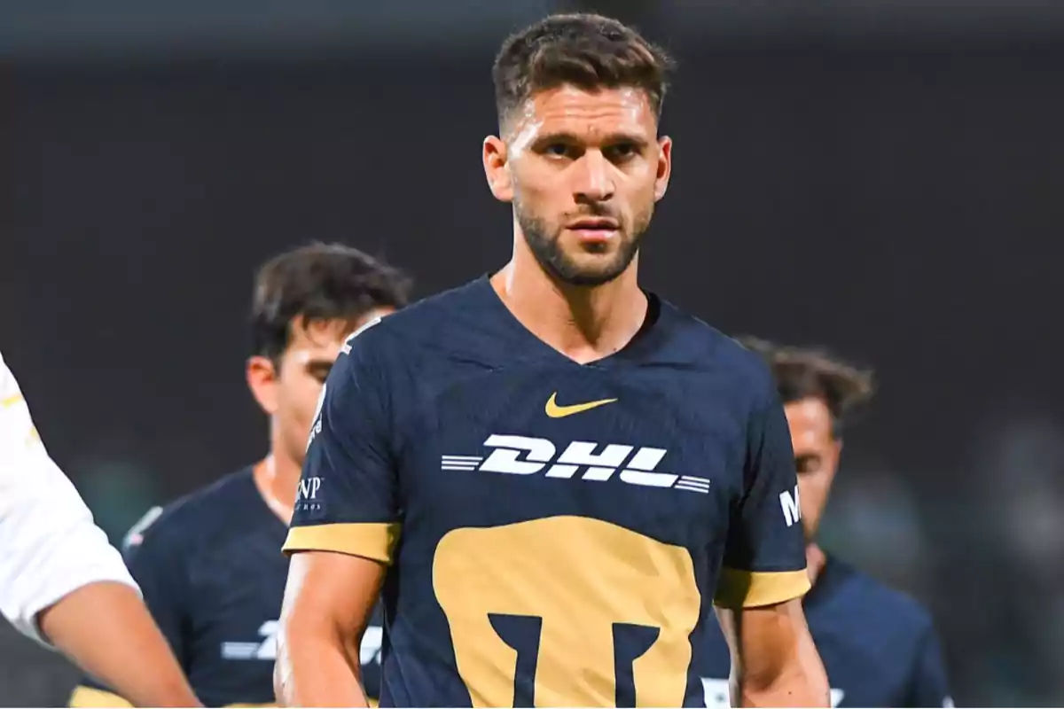 Un jugador de fútbol con uniforme azul marino y detalles dorados está en el campo de juego. Un jugador de fútbol con uniforme azul marino y detalles dorados está en el campo de juego.