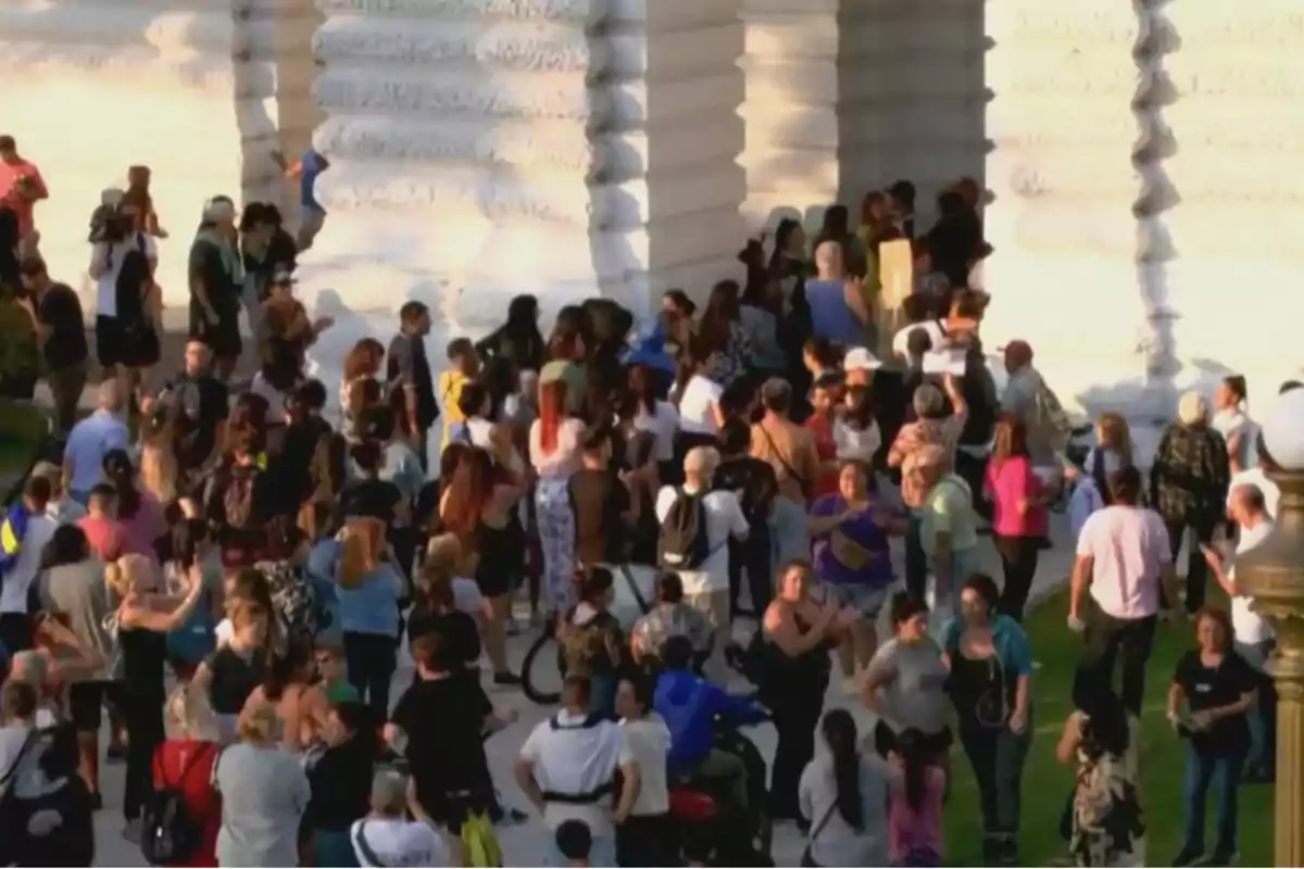 Una multitud de personas reunidas al aire libre cerca de un edificio con columnas blancas.