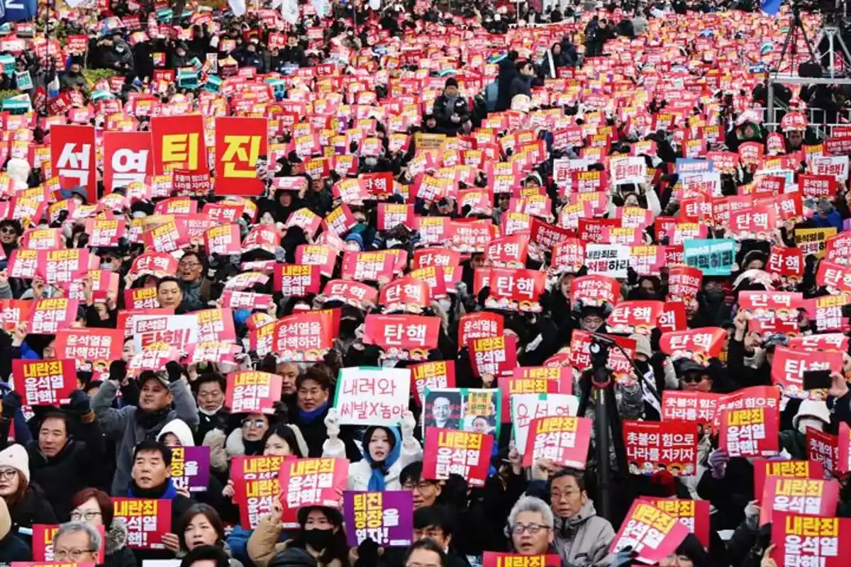 Una multitud de personas sosteniendo pancartas rojas y amarillas en una manifestación.