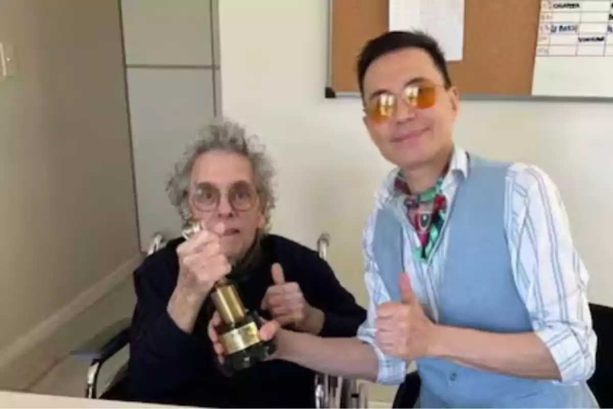 Dos personas posando con un trofeo en una habitación.