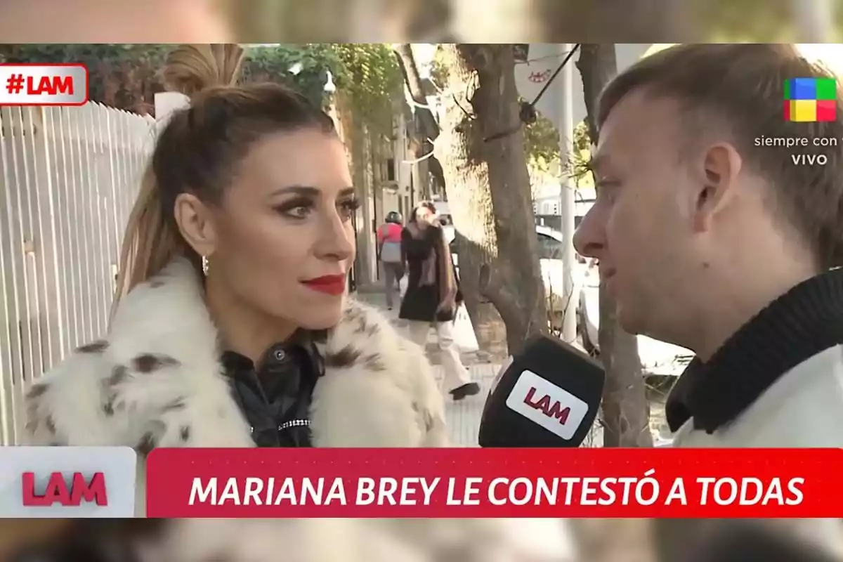 A woman in a fur coat and striking makeup is interviewed by a man on the street during a television show called LAM, with on-screen text that reads A woman in a fur coat and striking makeup is interviewed by a man on the street during a television show called LAM, with on-screen text that reads