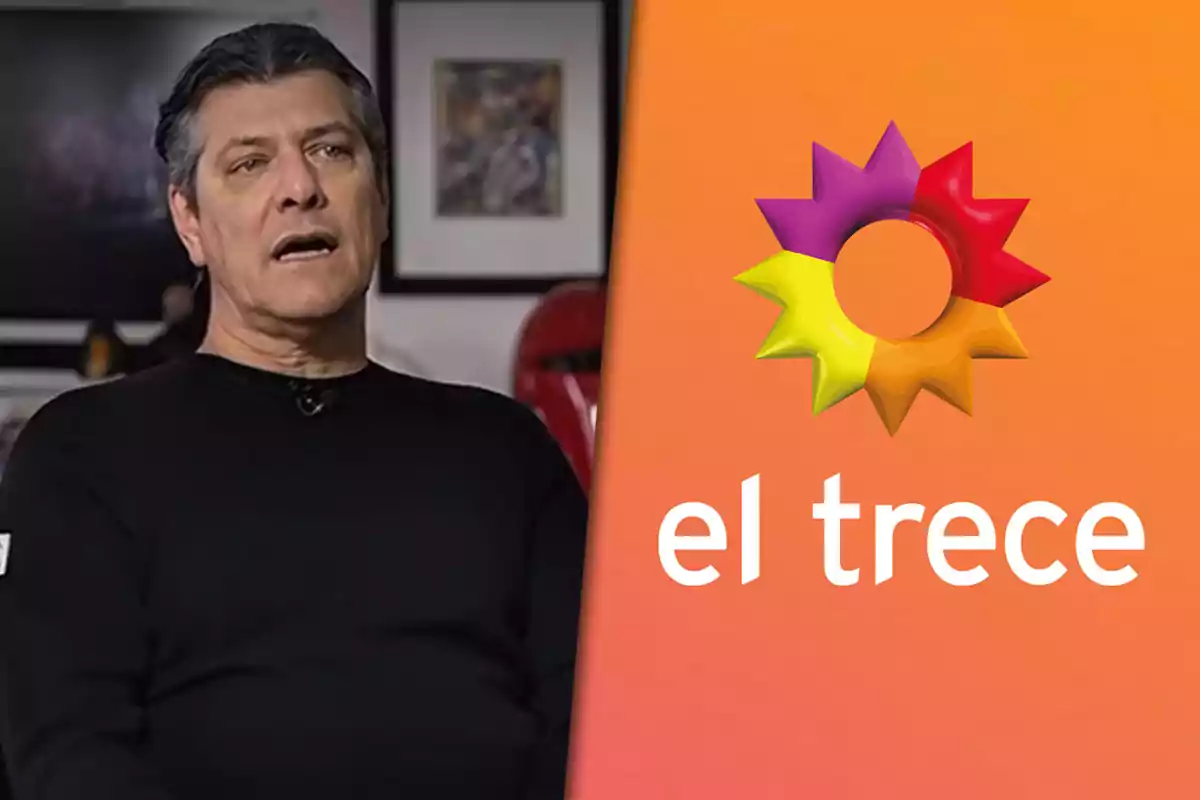 Hombre de cabello canoso con suéter negro sentado en un ambiente interior junto al logo colorido y el nombre del canal de televisión El Trece sobre un fondo naranja