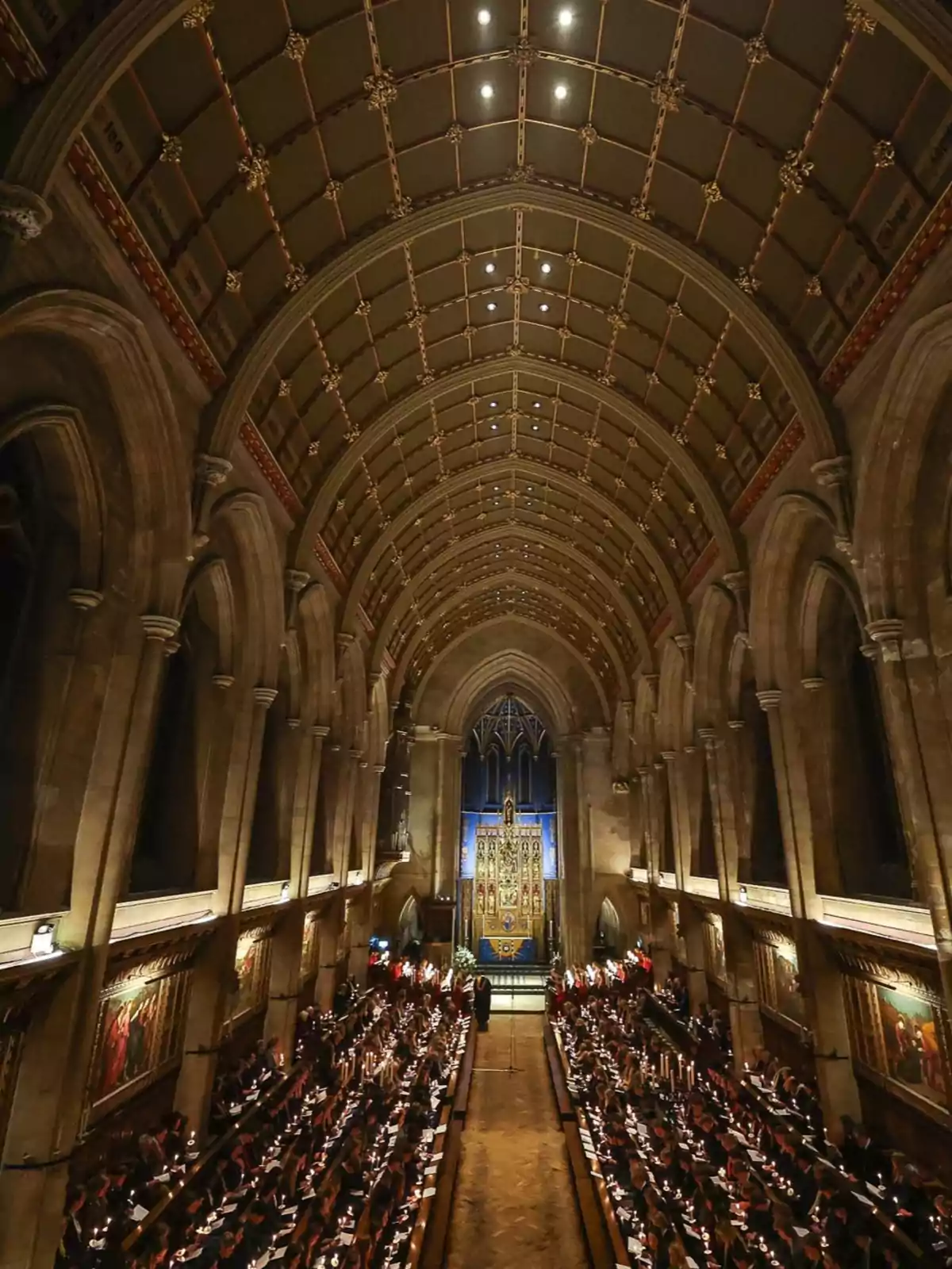 Interior de una iglesia con un techo abovedado y decoraciones detalladas, donde se celebra una ceremonia con muchas personas sentadas a ambos lados del pasillo central. Interior de una iglesia con un techo abovedado y decoraciones detalladas, donde se celebra una ceremonia con muchas personas sentadas a ambos lados del pasillo central.