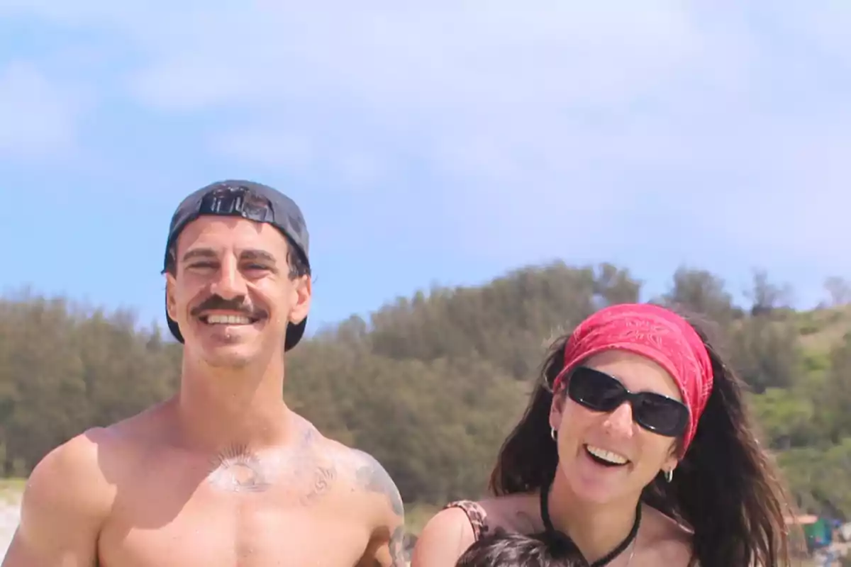 Una pareja sonriente en la playa con un fondo de árboles y cielo azul. Una pareja sonriente en la playa con un fondo de árboles y cielo azul.