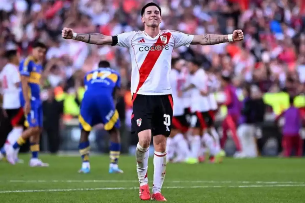 River Plate player celebrating with arms wide open in a packed stadium during a match against Boca Juniors River Plate player celebrating with arms wide open in a packed stadium during a match against Boca Juniors