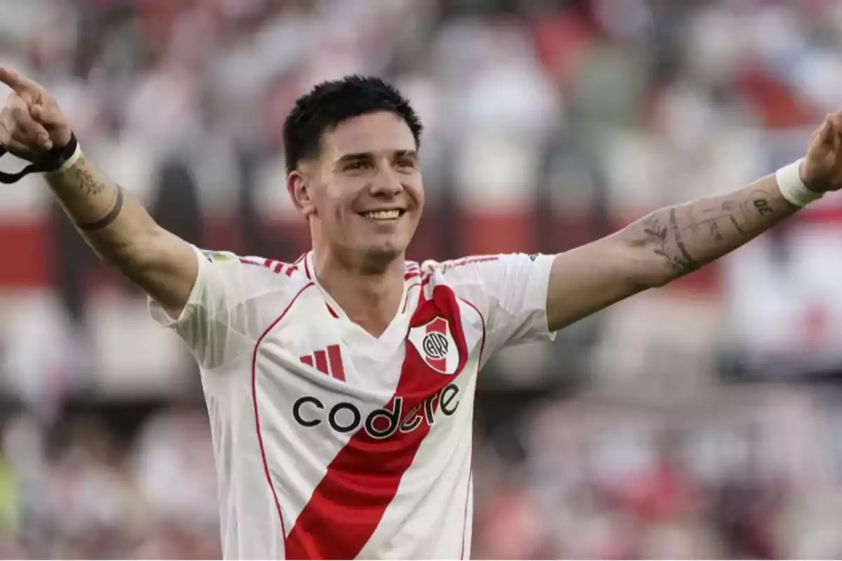 Un jugador de fútbol celebrando con los brazos extendidos en un estadio.