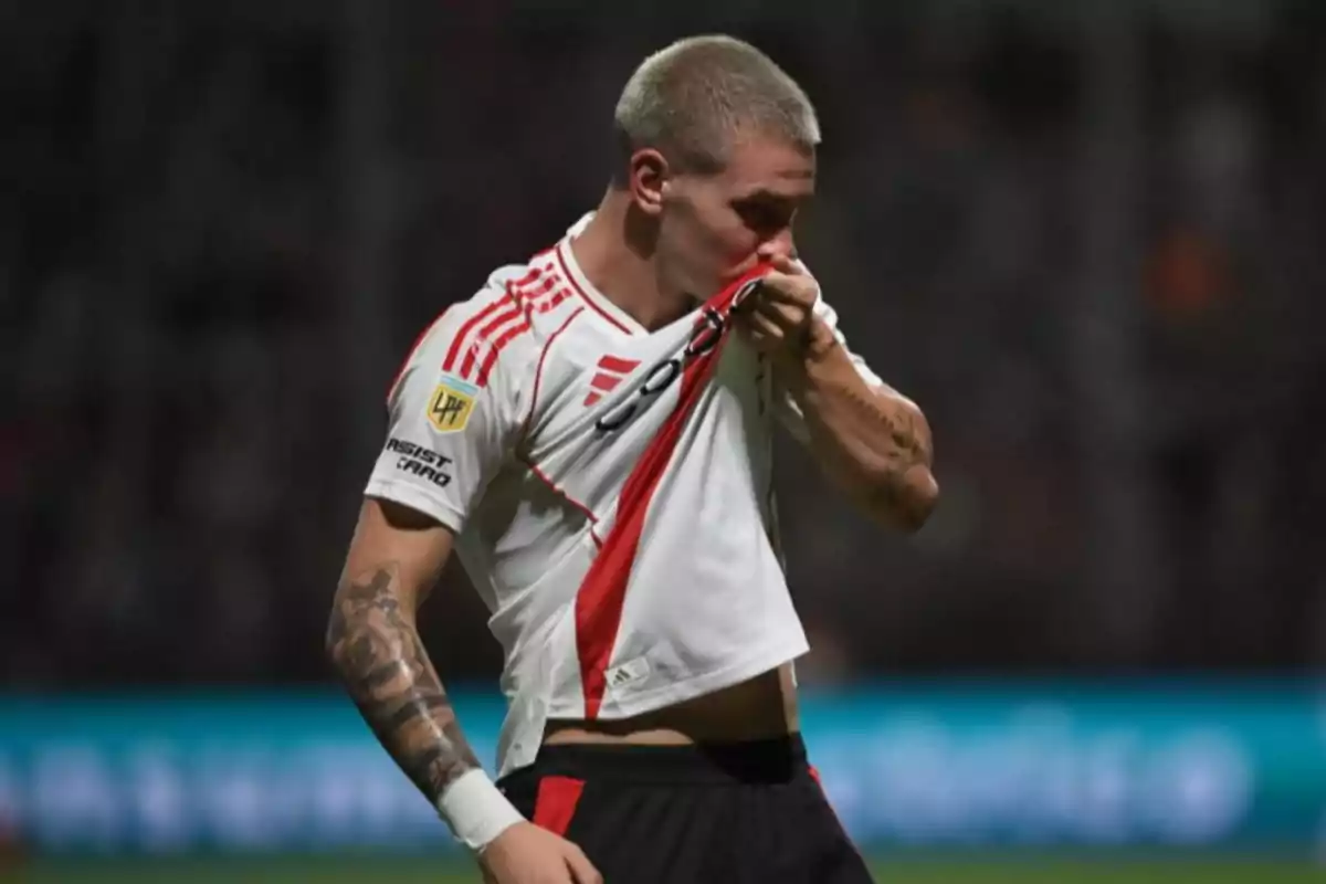 Futbolista besando el escudo de su camiseta durante un partido Futbolista besando el escudo de su camiseta durante un partido