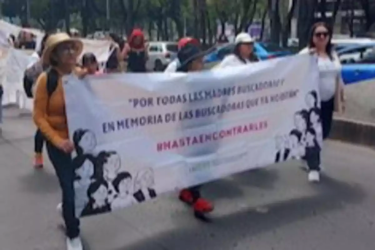 Un grupo de personas marcha por la calle sosteniendo una pancarta que rinde homenaje a las madres buscadoras. Un grupo de personas marcha por la calle sosteniendo una pancarta que rinde homenaje a las madres buscadoras.