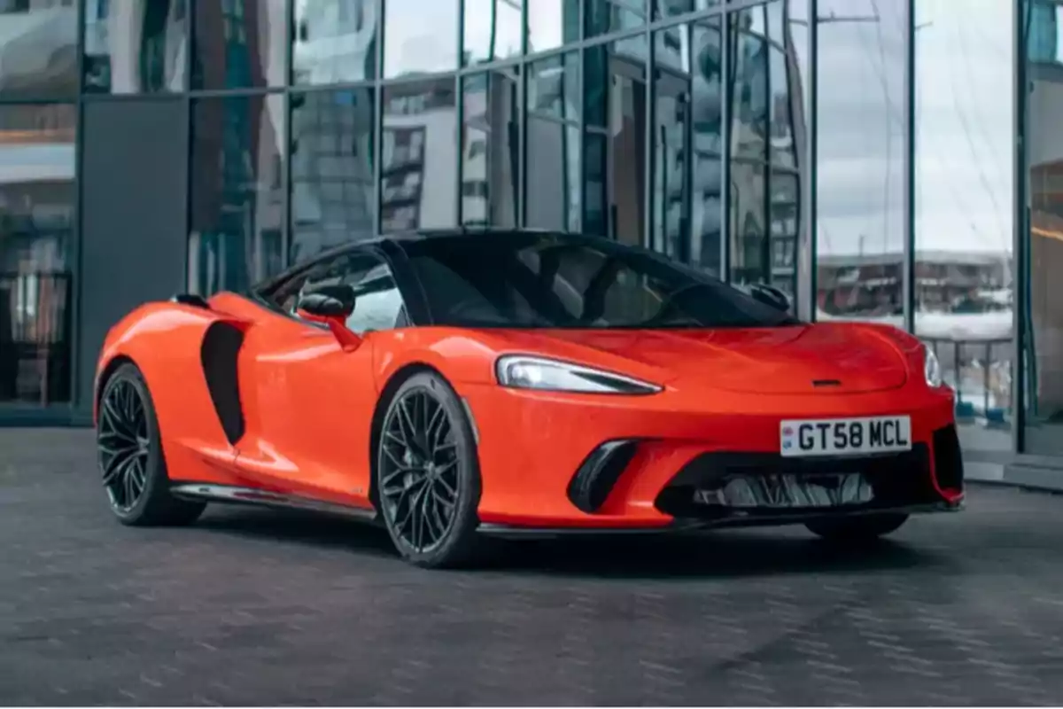 Orange sports car parked in front of a modern building with glass windows Orange sports car parked in front of a modern building with glass windows