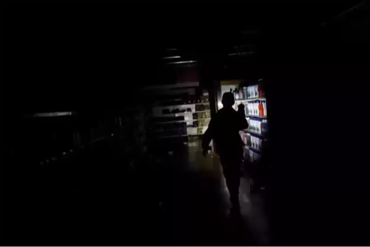 Una persona caminando en un pasillo oscuro de un supermercado iluminado por una linterna.