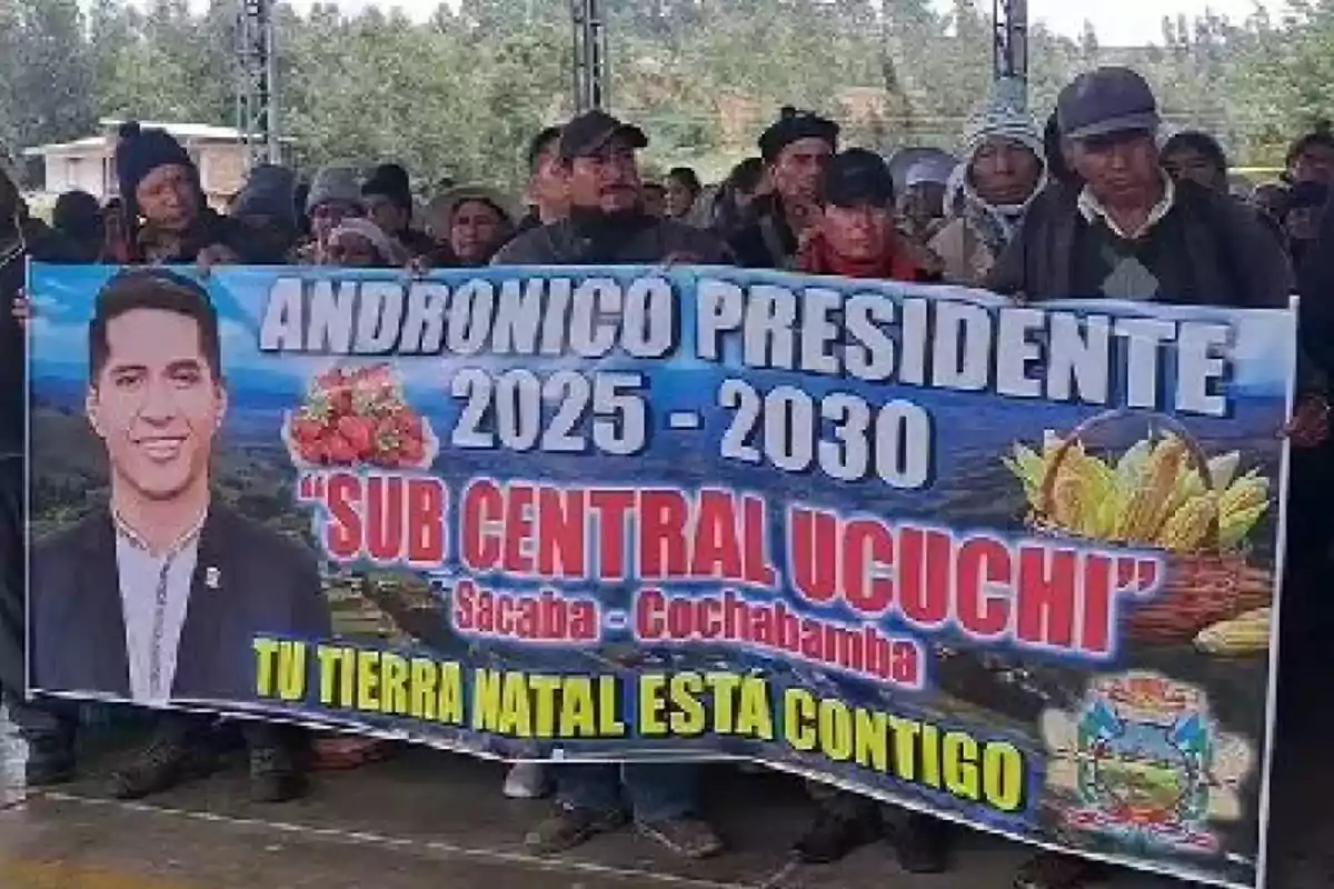 Un grupo de personas sostiene un cartel que promueve a un candidato presidencial para el período 2025-2030, con imágenes de productos agrícolas y un mensaje de apoyo de su tierra natal.