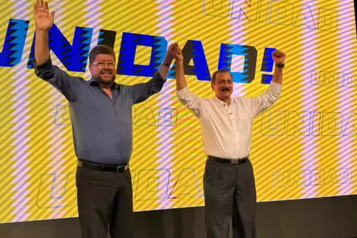 Two people raise their hands together in front of a yellow background with the word "UNITY" in large letters.