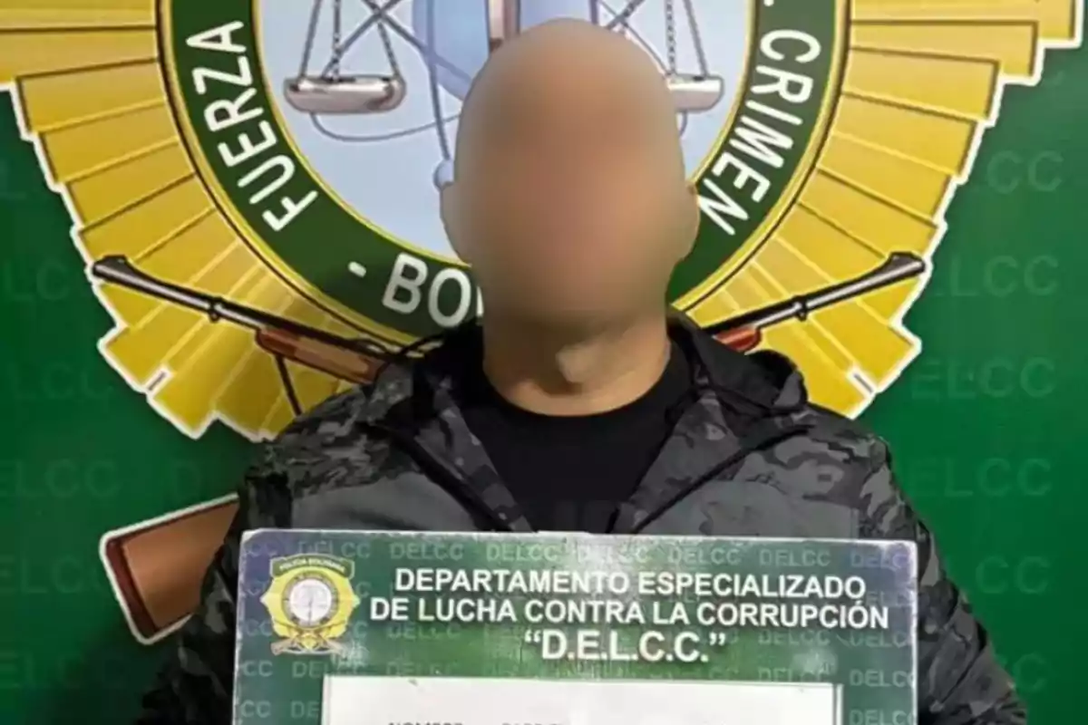 Un individuo con el rostro difuminado sostiene un cartel del Departamento Especializado de Lucha Contra la Corrupción frente a un emblema oficial.