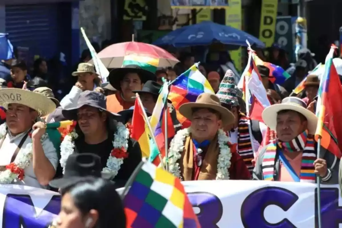 Personas marchando en la calle con banderas multicolores y vestimenta tradicional andina Personas marchando en la calle con banderas multicolores y vestimenta tradicional andina