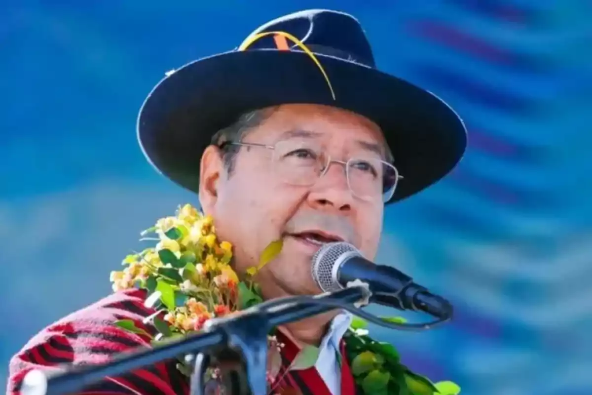 Hombre con sombrero y gafas hablando frente a un micrófono con un collar de flores y hojas Hombre con sombrero y gafas hablando frente a un micrófono con un collar de flores y hojas