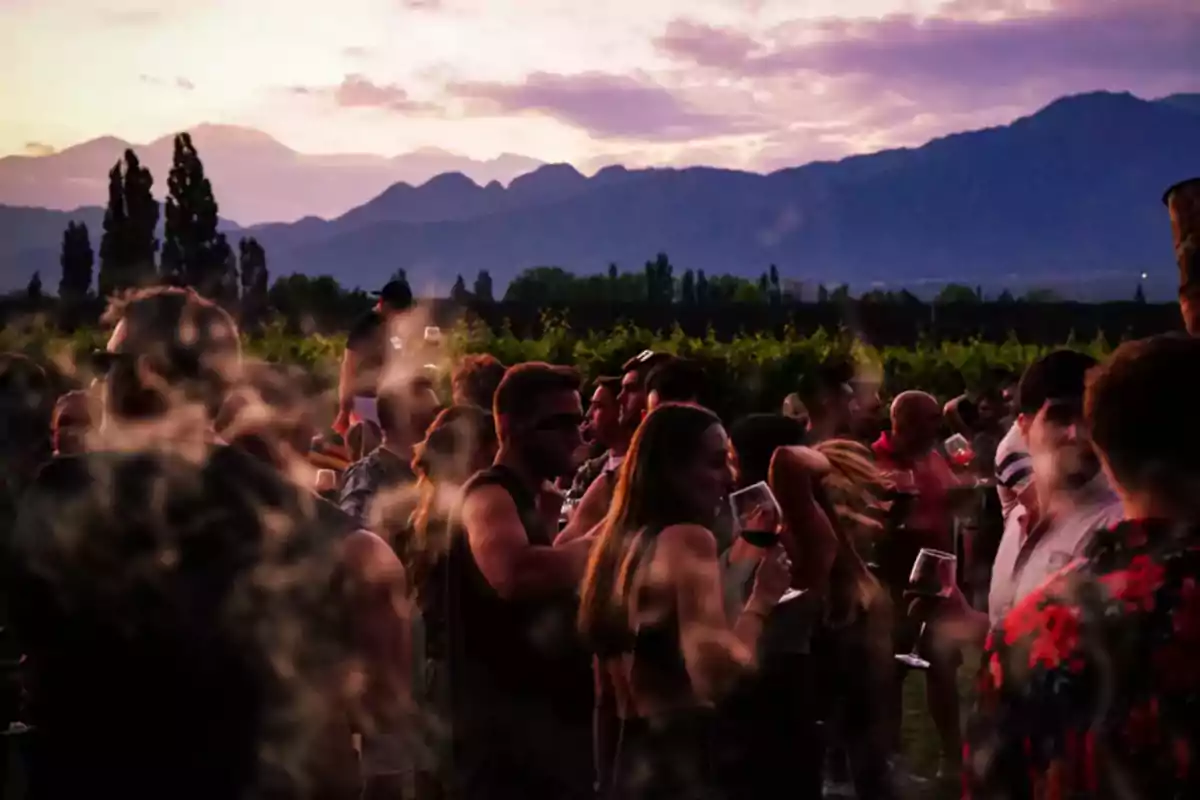 Grupo de personas disfrutando de una reunión al aire libre al atardecer con montañas al fondo.