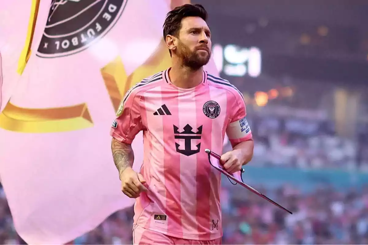 Futbolista con uniforme rosa del Inter Miami corriendo en el campo con una bandera de fondo