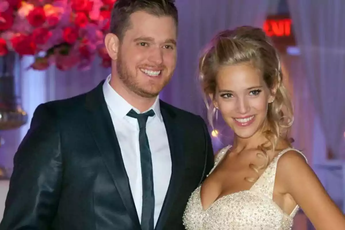 Una pareja sonriente vestida de manera elegante en un evento con decoración de flores rosas. Una pareja sonriente vestida de manera elegante en un evento con decoración de flores rosas.