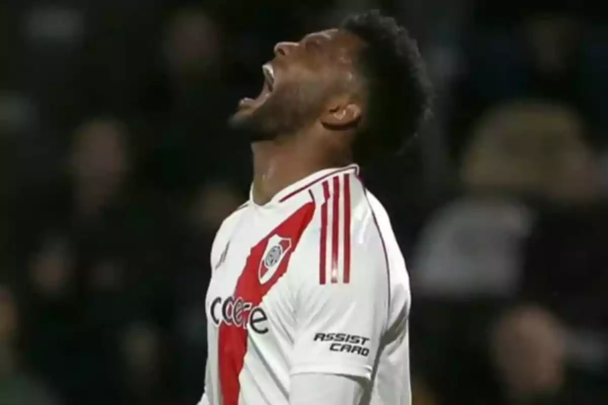 Jugador de fútbol con uniforme blanco y rojo gritando con emoción durante un partido.