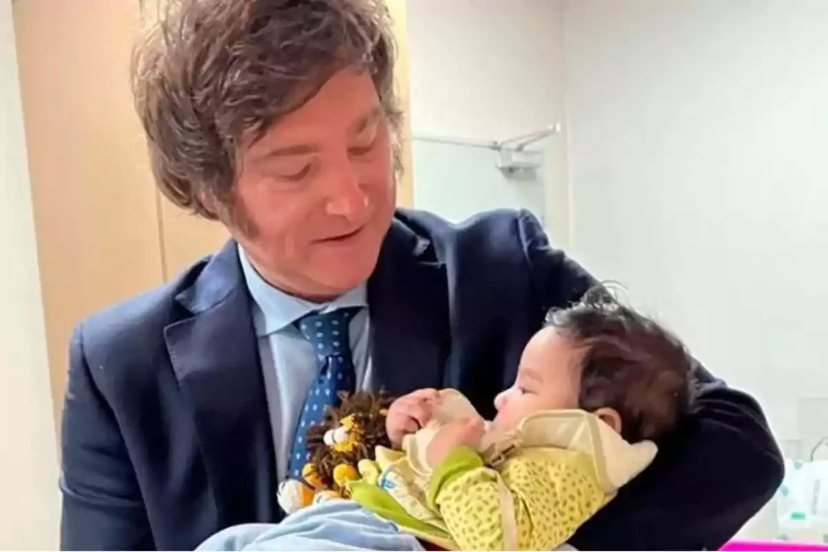 Man in a blue suit holds a baby dressed in yellow clothes in a brightly lit room. Man in a blue suit holds a baby dressed in yellow clothes in a brightly lit room.