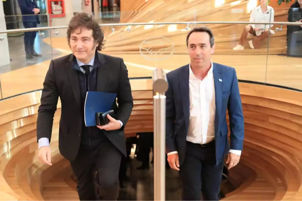 Two men climb a wooden ladder in a modern building with glass railings. Two men climb a wooden ladder in a modern building with glass railings.