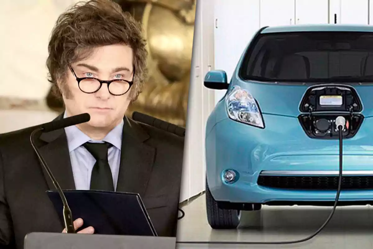 Un hombre con gafas y traje hablando frente a micrófonos junto a un auto eléctrico azul que está siendo cargado