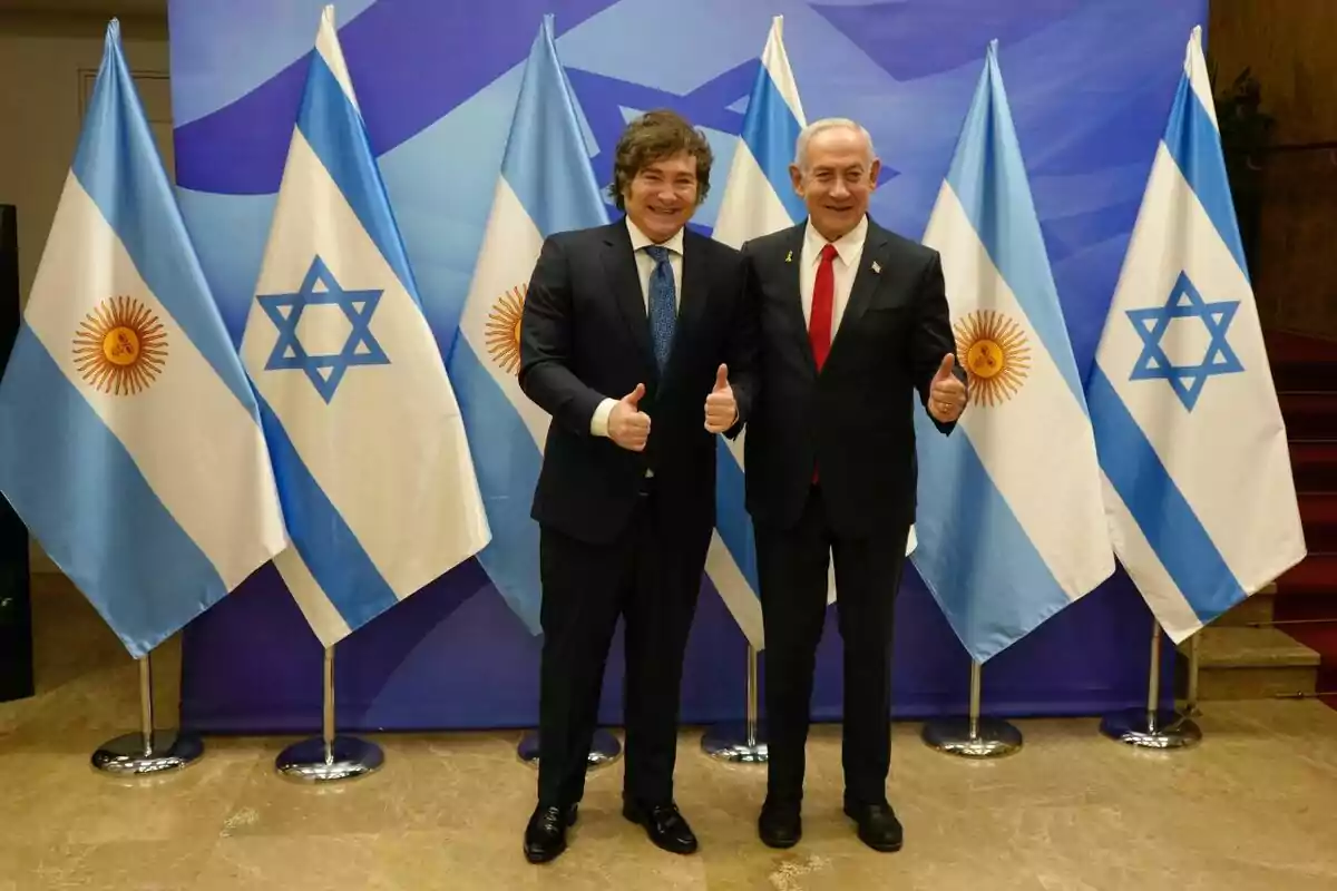 Dos hombres de traje posan sonrientes con el pulgar hacia arriba frente a banderas de Argentina e Israel Dos hombres de traje posan sonrientes con el pulgar hacia arriba frente a banderas de Argentina e Israel