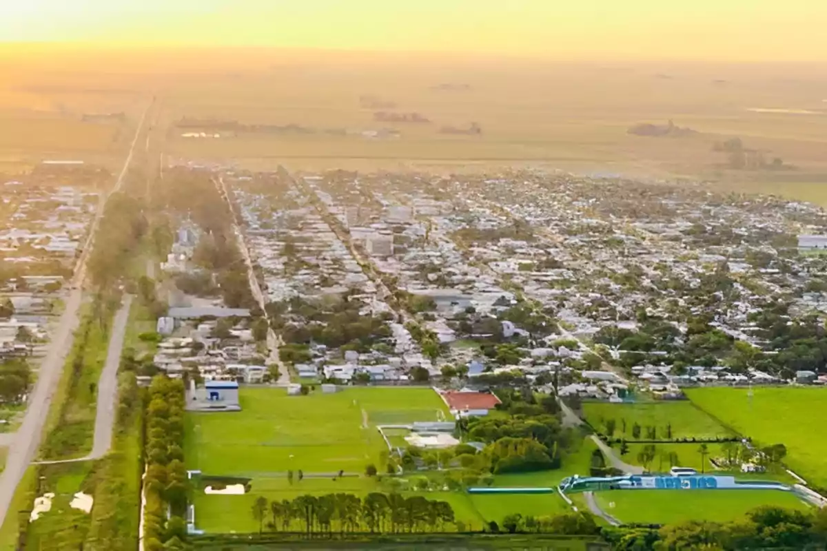 Aerial view of a city surrounded by green fields at sunset