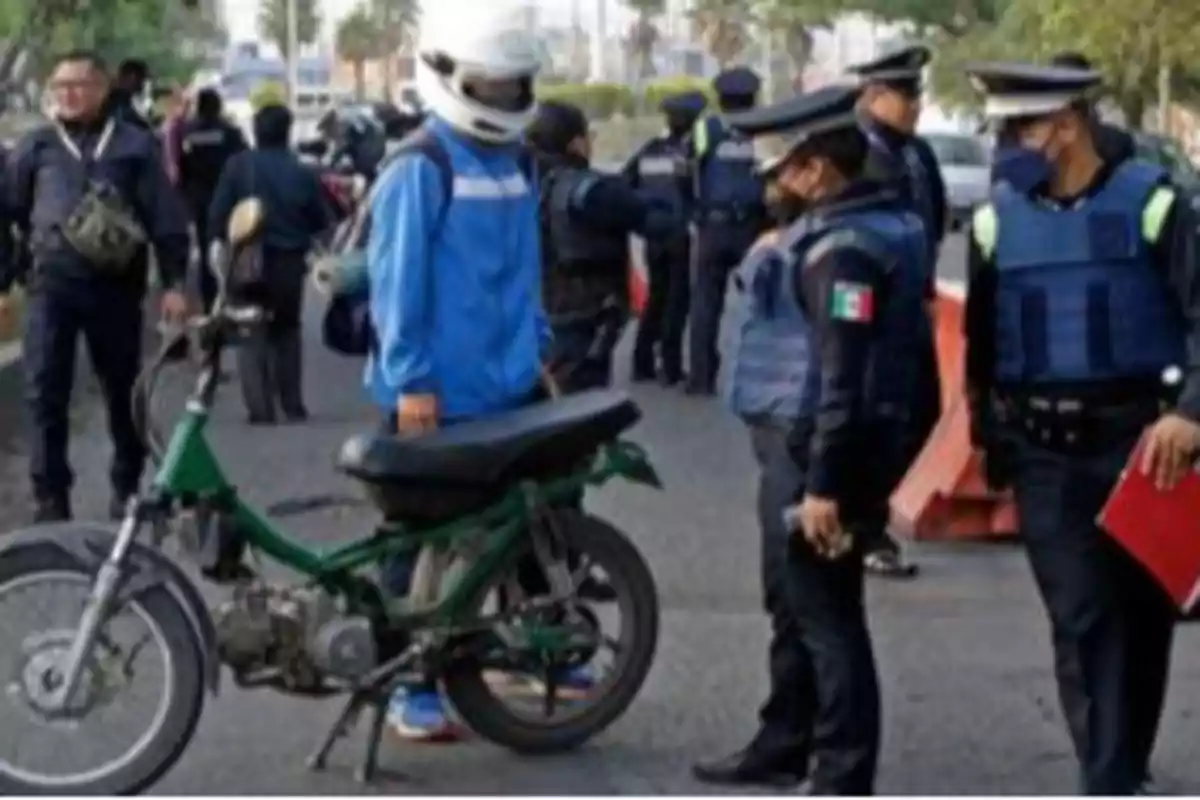 Un grupo de policías detiene a un motociclista en la calle para una revisión.