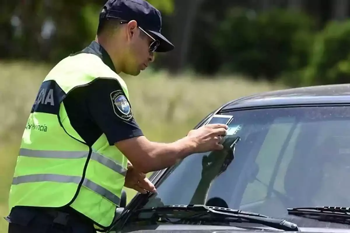 A police officer places a ticket on a car's windshield. A police officer places a ticket on a car's windshield.