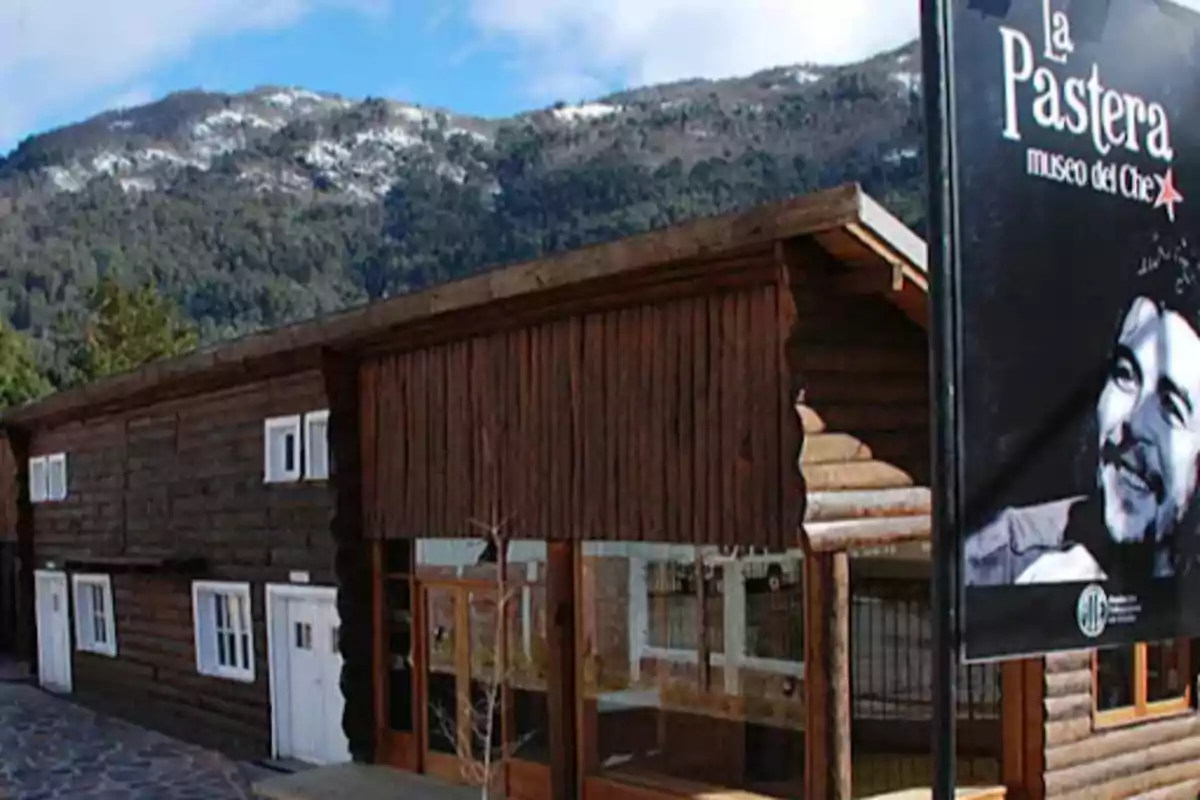 Edificio de madera rodeado de montañas con un cartel que anuncia el museo La Pastera dedicado al Che Edificio de madera rodeado de montañas con un cartel que anuncia el museo La Pastera dedicado al Che