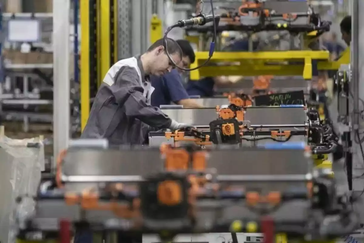 Trabajador ensamblando componentes en una línea de producción industrial