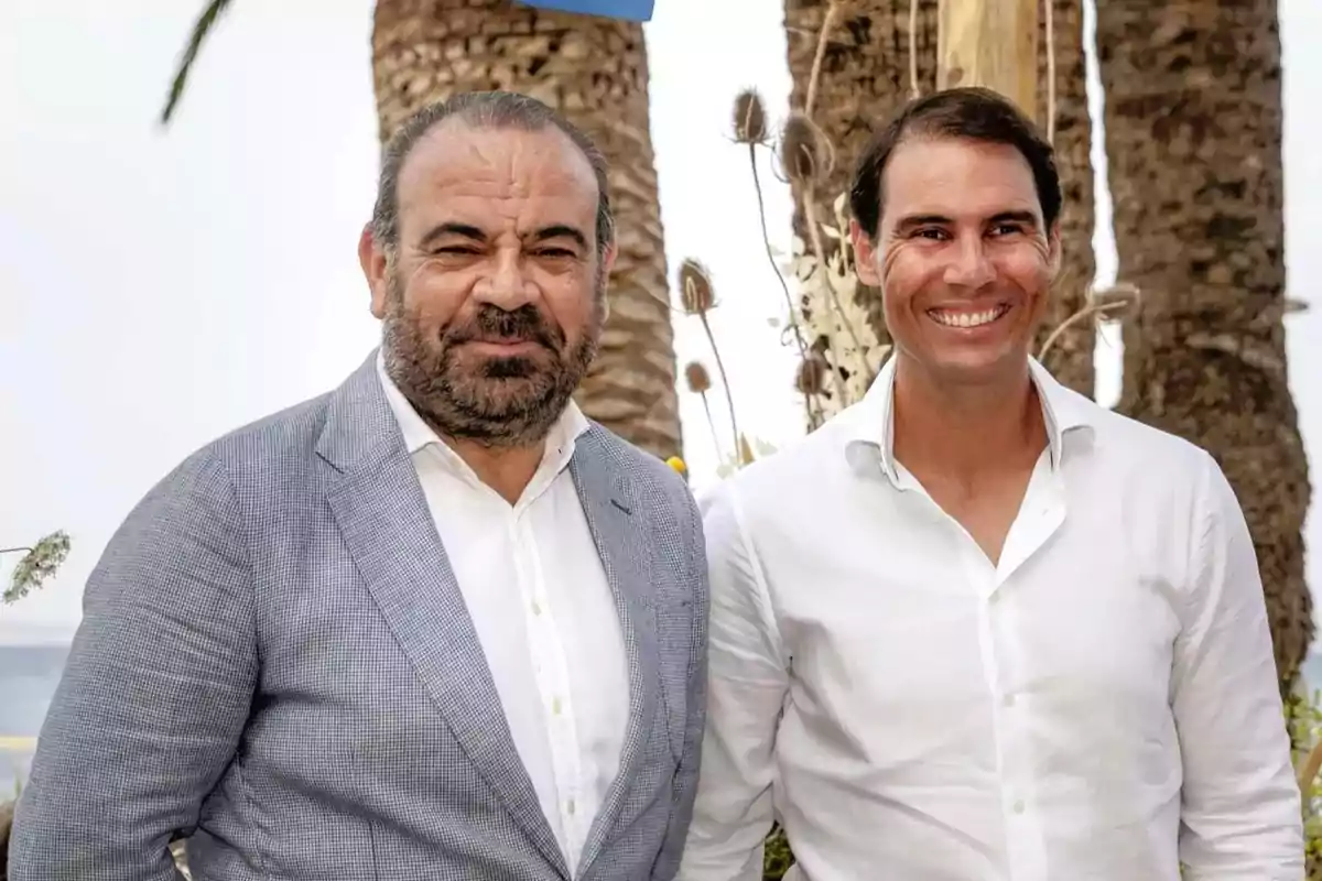 Dos hombres posan juntos al aire libre con palmeras de fondo. Dos hombres posan juntos al aire libre con palmeras de fondo.