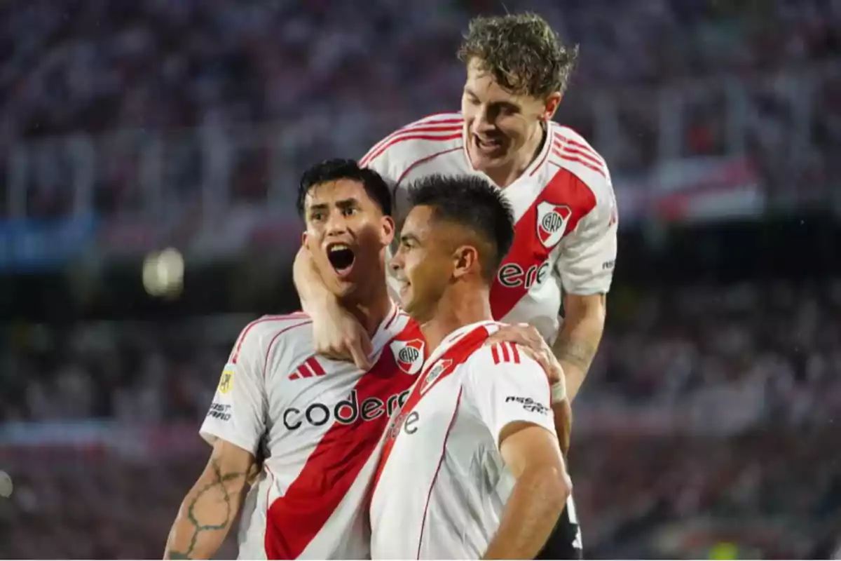 Jugadores de fútbol celebrando un gol con camisetas blancas y rojas en un estadio lleno de espectadores. Jugadores de fútbol celebrando un gol con camisetas blancas y rojas en un estadio lleno de espectadores.